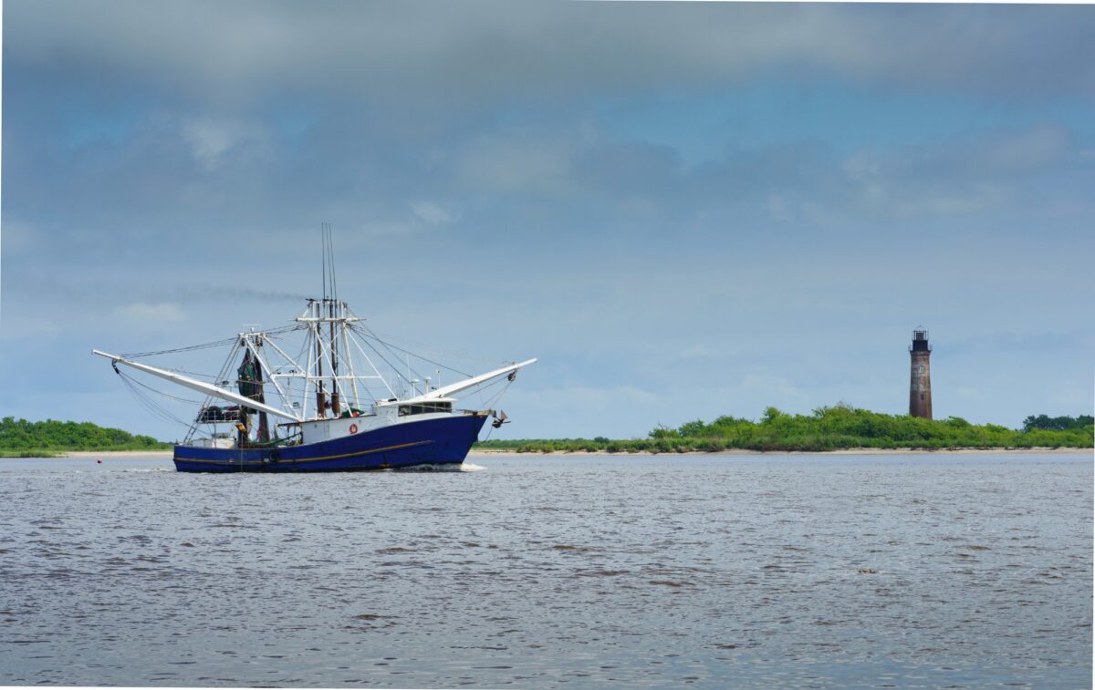 A shrimp boat passes the historic Sabine Pass Lighthouse.